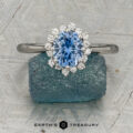 The "Celisse" ring in platinum, featuring a 1.27-carat Montana sapphire, is displayed on a rough blue mineral, with the "Earth's Treasury" logo below.