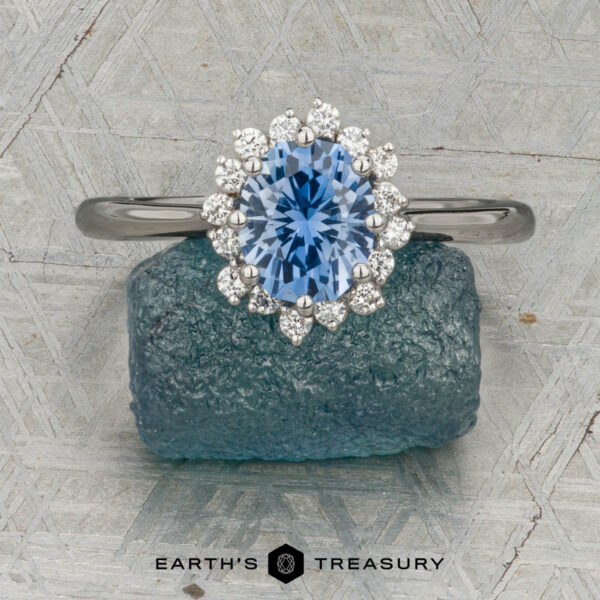 Custom ring in platinum with 1.27-carat Montana sapphire The "Celisse" ring in platinum, featuring a 1.27-carat Montana sapphire, is displayed on a rough blue mineral, with the "Earth's Treasury" logo below.