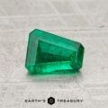 A 0.78-carat Zambia emerald (oiled) with a trapezoid shape is displayed on a textured surface above the Earth's Treasury logo.