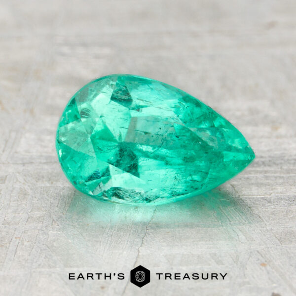 1.15-Carat Colombia Emerald (Oiled) A 1.15-carat pear-shaped, faceted Colombia emerald (oiled) rests on a light textured surface with the text "EARTH'S TREASURY" below.