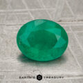 A 1.33-carat oval-cut Colombia emerald (oiled) is displayed on a textured gray surface with "Earth's Treasury" at the bottom.