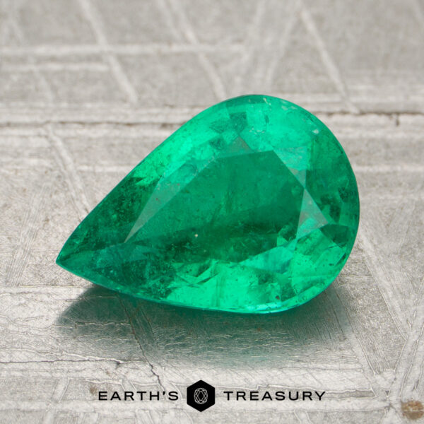 1.76-Carat Zambia Emerald (Oiled) A 1.76-carat pear-shaped Zambia emerald (oiled) sits on a textured metallic surface, with the "EARTH'S TREASURY" logo displayed at the bottom.