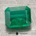 A 2.89-carat Zambia emerald (oiled) in an emerald cut rests on a textured silvery surface, with "Earth's Treasury" shown below.