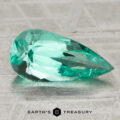 A 1.39-carat faceted, pear-shaped Colombia emerald (oiled) is displayed on a textured metallic surface with "Earth's Treasury" below.