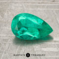 A faceted, pear-shaped 1.24-carat Colombia emerald (oiled) rests on a textured gray surface with the “Earth’s Treasury” logo below.