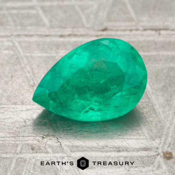 1.27-Carat Colombia Emerald (Oiled) A 1.27-carat Colombia emerald (oiled), pear-shaped and green, is shown on a textured metallic surface with the "Earth's Treasury" logo and text at the bottom.