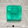 A 1.65-carat oiled Colombia emerald with a rectangular cut is displayed on a textured surface, featuring the "Earth's Treasury" logo and text at the bottom of the image.