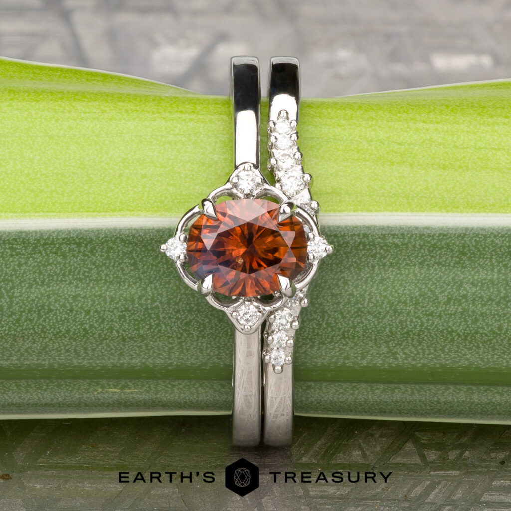 The "Sharpe, Jason 1 & 2" ring features a round orange gemstone with small white stones in a silver setting, displayed on a green stem with the "Earth's Treasury" logo—an elegant choice among women's wedding bands.