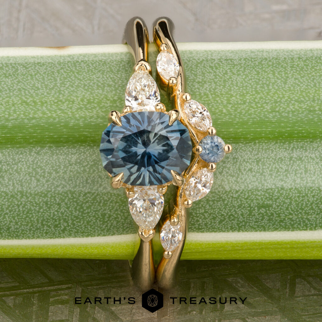 A gold ring set with a blue oval gemstone and marquise-cut clear stones, "Stacked from 41 images. Method=B (R=14,S=2)," is shown on a green leaf with the text "EARTH'S TREASURY" at the bottom.