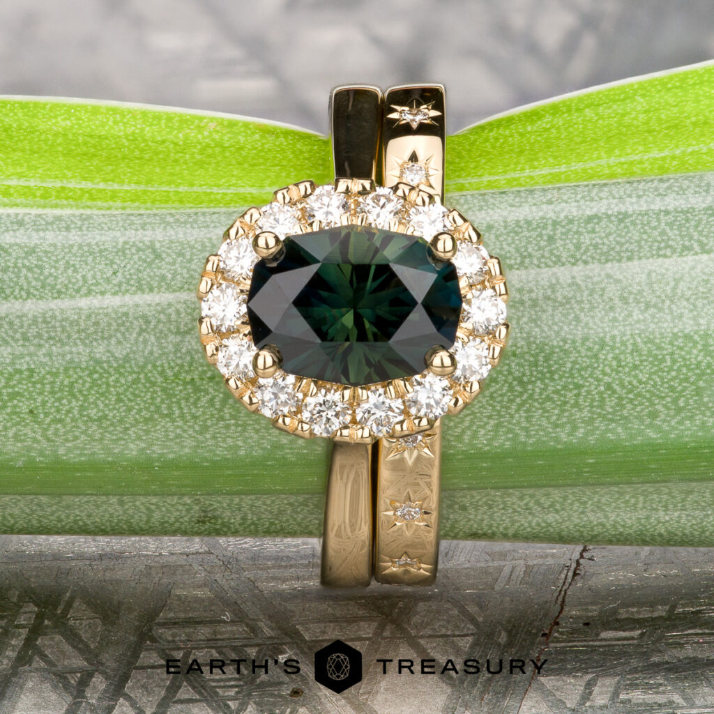 The Ferraro, Jordan 1 & 2—a gold ring with an oval green gemstone and diamonds, paired with a matching band from our Womens Wedding Bands collection—displayed elegantly on a green leaf.