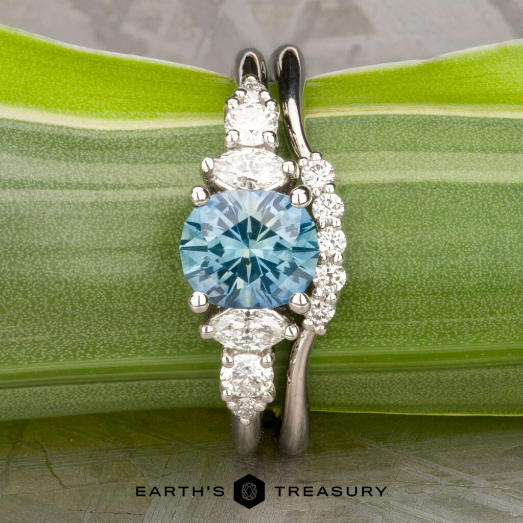 Displayed on a green leaf, "Stacked from 41 images. Method=B (R=8,S=4)" is a unique silver women's wedding band with a round blue gemstone center and multiple white diamonds. The "Earth's Treasury" logo appears at the bottom.