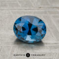 A 1.64-carat unheated sapphire with an oval cut is showcased on a textured gray surface, featuring the text "Earth's Treasury" and a logo beneath.