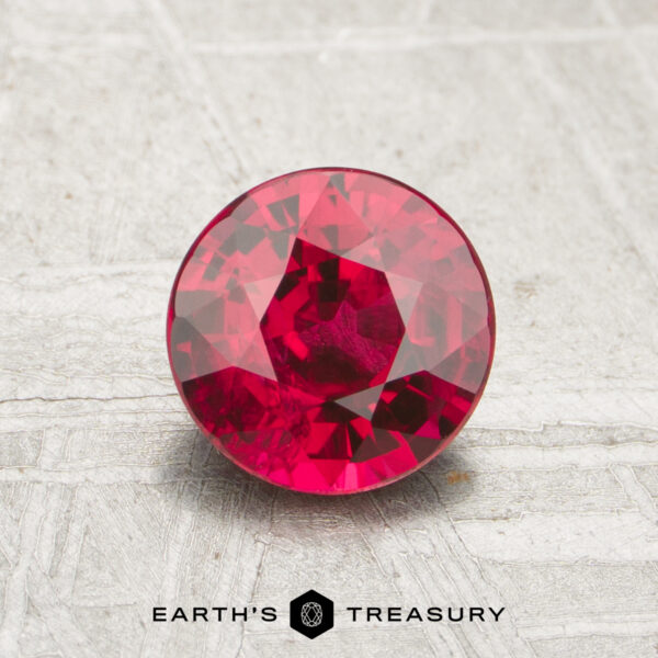 1.12-Carat Ruby A 1.12-carat round, faceted ruby is displayed on a textured gray surface with the "Earth's Treasury" logo beneath it.