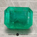A 5.07-carat rectangular emerald gemstone with visible inclusions rests on a textured surface, the Earth's Treasury logo displayed beneath it.