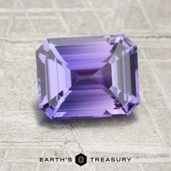 A 2.09-carat unheated Sapphire, rectangular and faceted with a purple hue, displayed on a textured light background with "Earth's Treasury" written beneath.