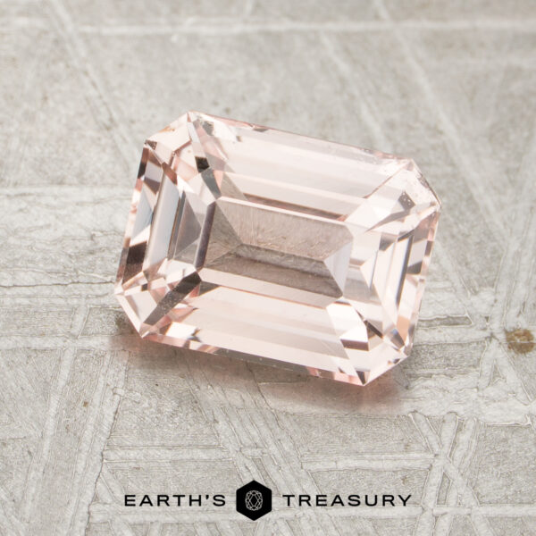 2.05-Carat Peach Madagascar Sapphire (Unheated) A rectangular, peack pink 2.05-carat unheated sapphire with beveled edges rests on a textured metallic surface. "EARTH’S TREASURY" is printed at the bottom of the image.