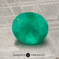 A 2.16-carat oval-cut emerald rests on a textured metallic surface with the words "EARTH'S TREASURY" at the bottom.