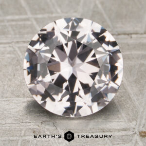 A 3.48-carat round brilliant-cut sapphire is displayed on a light, patterned surface with the text "Earth's Treasury" and a logo beneath it.