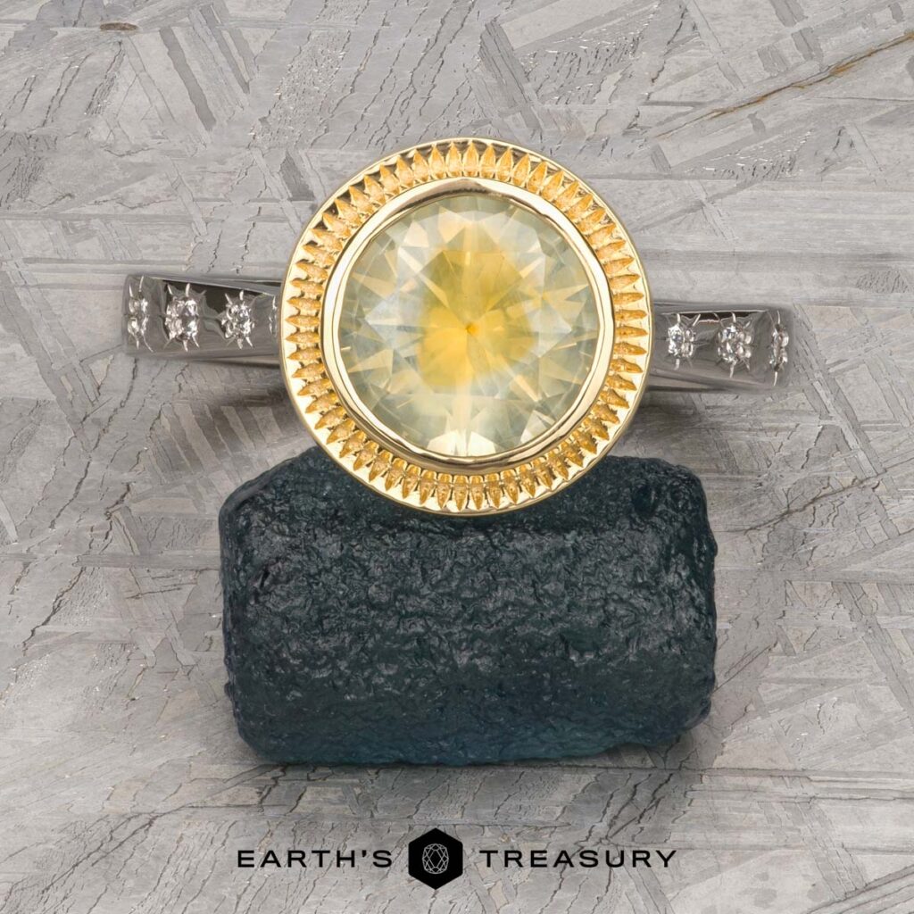 The Ramadas, Rohan 2 ring—a yellow gemstone set in a gold bezel with diamond-accented silver band—is displayed on dark stone, with the "Earth's Treasury" logo below.