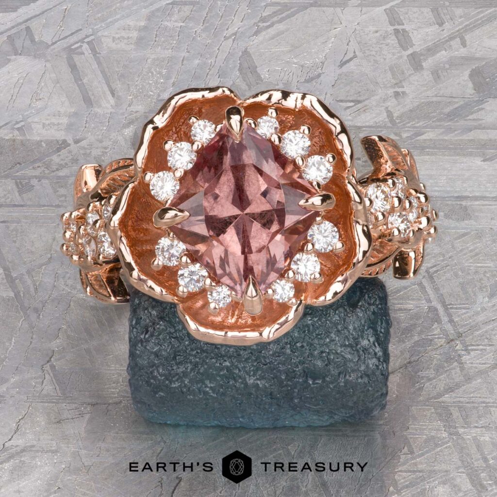 The Ford, Kyleih [custom gallery] features a rose gold ring with a large pink gemstone and small white diamonds in a floral design, showcased on rough stone with the Earth's Treasury logo displayed below.