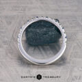 A platinum Hand-Cut Pave Yogo Band ring with a jagged, mountain-inspired top edge stands upright before a dark stone on a geometric surface. "Earth's Treasury" appears at the bottom of the image.