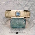 The "Montserrat" ring in 14K yellow gold with teal sapphire is shown on a rough blue stone, Earth's Treasury logo below. Ready to ship.