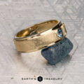The "Montserrat" ring in 14K yellow gold with teal sapphire is shown on a rough blue stone, Earth's Treasury logo below. Ready to ship.
