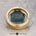 The "Montserrat" ring in 14K yellow gold with teal sapphire is shown on a rough blue stone, Earth's Treasury logo below. Ready to ship.