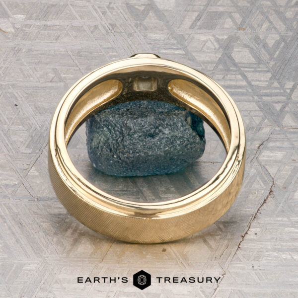 The "Montserrat" ring in 14K yellow gold with teal sapphire The "Montserrat" ring in 14K yellow gold with teal sapphire is shown on a rough blue stone, Earth's Treasury logo below. Ready to ship.