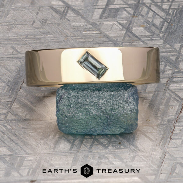 The "Eiger" Ring A gold ring featuring a rectangular green gemstone from our ET Stock collection in 14K Yellow Gold is shown balanced atop a rough blue-green stone, with the Earth’s Treasury logo and text below. Ready to Ship.