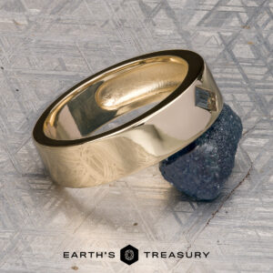 A gold ring showcasing a rectangular gemstone, expertly crafted in 14K Yellow Gold, sits atop a raw mineral on a textured metallic surface. "EARTH’S TREASURY" and a logo are featured at the bottom of the image. This ET Stock ring is ready to ship.