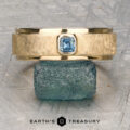 A gold textured ring named "Stacked from 49 images. Method=B (R=7,S=2)" with a square blue gemstone in a Florentine Finish is displayed on a rough blue stone. The text "Earth's Treasury" appears at the bottom.