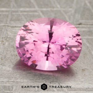 2.08-carat oval-cut pink sapphire displayed on a textured gray surface with the "Earth's Treasury" logo at the bottom.