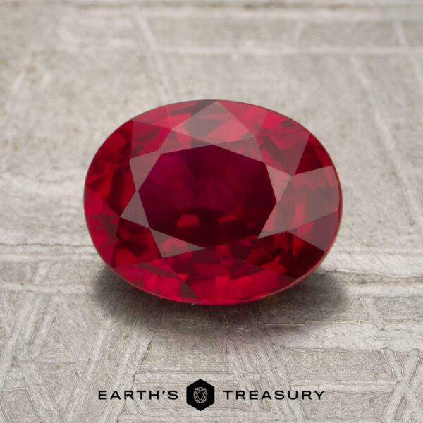 2.20-Carat Mozambique Ruby (Heated) A 2.20-carat ruby, faceted in an oval shape, rests on a textured metallic surface with the Earth's Treasury logo and text below.