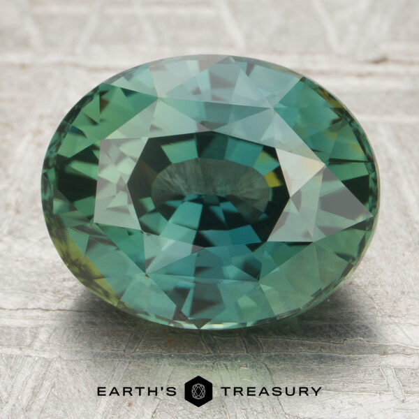 4.69-Carat Sapphire (Heated) 4.69-carat heated sapphire in round brilliant cut displayed on textured surface with "Earth's Treasury" logo beneath.