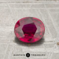 A 1.27-carat oval ruby is displayed on a textured metallic surface with the text "EARTH'S TREASURY" below.