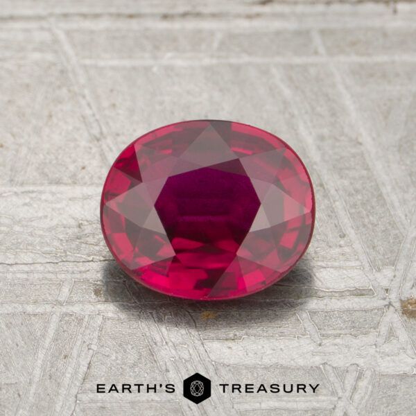 1.27-Carat Mozambique Ruby (Heated) A 1.27-carat oval ruby is displayed on a textured metallic surface with the text "EARTH'S TREASURY" below.