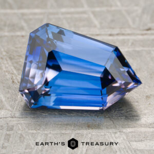 A 3.01-carat heated sapphire with angular facets rests on a textured surface, displayed above the Earth's Treasury logo and text.