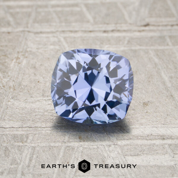 A 1.32-carat unheated Ceylon sapphire with a cushion cut is displayed on a textured surface, with "Earth's Treasury" shown below.
