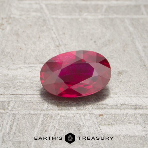 0.50-Carat Mozambique Ruby (Heated) A 0.50-carat faceted ruby in an oval shape is displayed on a textured gray background with the "Earth's Treasury" logo at the bottom.