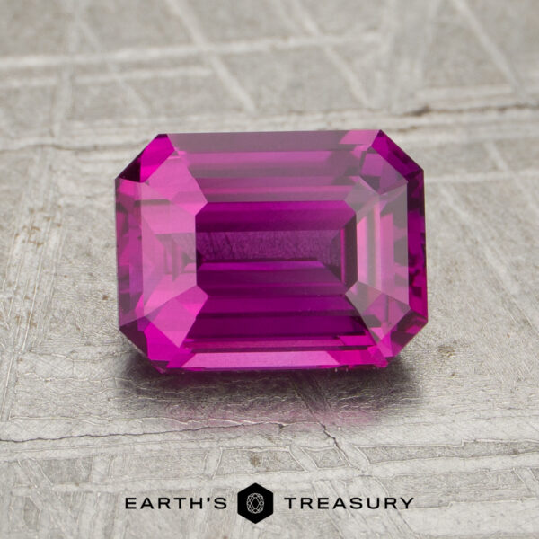 2.05-Carat Hot Pink Ceylon Sapphire (Heated) Rectangular emerald-cut 2.05-carat heated sapphire in bright pink, displayed on a textured metallic surface with the text "Earth's Treasury" at the bottom.