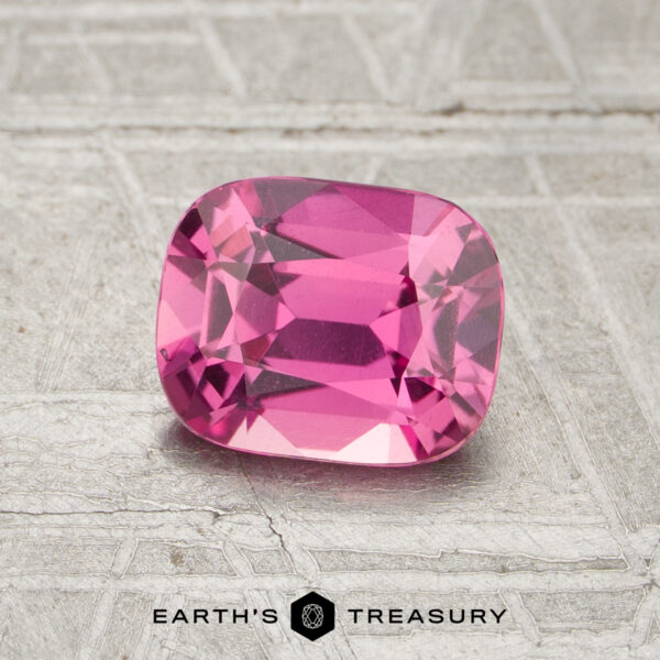 1.30-Carat Pink Ceylon Sapphire (Heated) A 1.30-carat heated sapphire with a cushion cut is displayed on a textured metallic surface featuring the "Earth's Treasury" logo at the bottom.