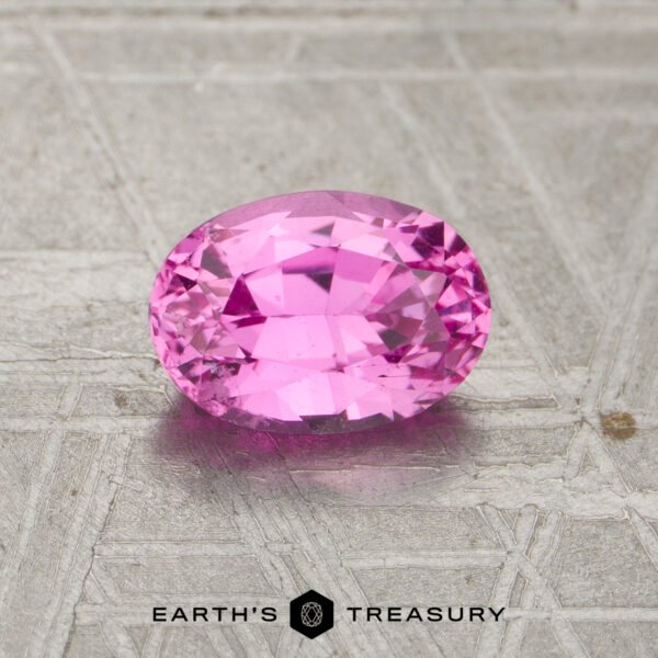 1.16-Carat Pink Madagascar Sapphire (Heated) Oval-cut pink 1.16-carat heated sapphire on a textured metallic surface, with "Earth's Treasury" and logo text at the bottom of the image.