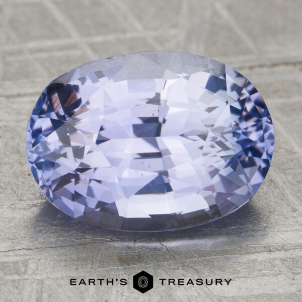 4.12-Carat Light Violet Ceylon Sapphire (Unheated) Unheated 4.12-carat oval-cut light violet sapphire with facets rests on a textured surface. "EARTH'S TREASURY" logo and text appear at the bottom of the image.