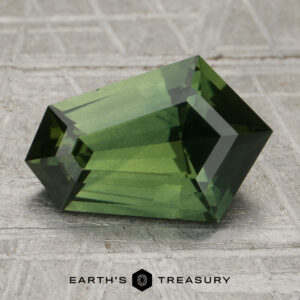 A 2.54-carat unheated sapphire with geometric facets is displayed on a textured gray surface, with the "Earth's Treasury" logo beneath it.
