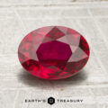 A 1.72-carat faceted oval ruby rests on a light textured surface, with the Earth’s Treasury logo and name displayed at the bottom.