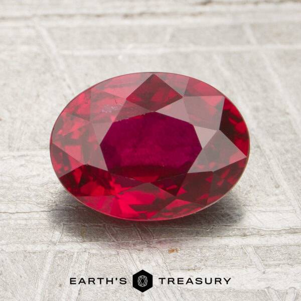 1.72-Carat Ruby A 1.72-carat faceted oval ruby rests on a light textured surface, with the Earth’s Treasury logo and name displayed at the bottom.