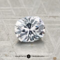 A 1.04-carat round brilliant Montana sapphire with angular facets rests on a textured gray surface; the "Earth's Treasury" logo is shown at the bottom.