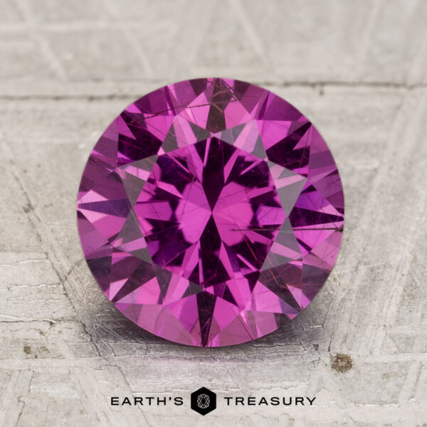 3.12-Carat Pastel Pyrope Garnet A 3.12-carat Pastel Pyrope Garnet, round and faceted, is shown on a textured, light background with "EARTH'S TREASURY" at the bottom.