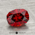A 2.99-carat Spessartine Garnet with a brilliant cut is displayed on a textured, light gray surface. The Earth's Treasury logo appears at the bottom of the image.